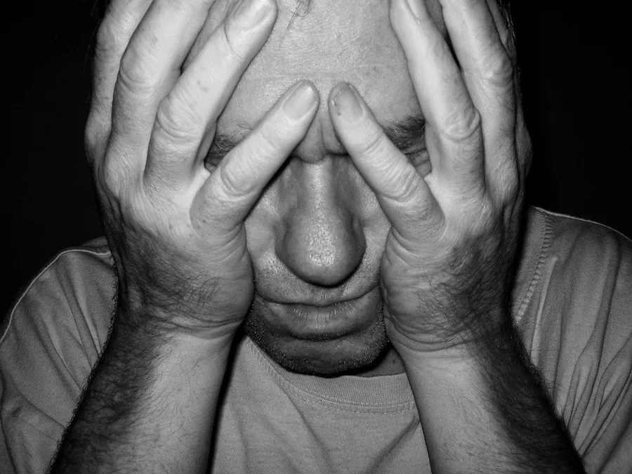 Stressed adult with head in hands